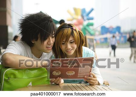 Teenage couple sitting at sidewalk cafe, looking at menu View Large Photo Image Stock Photo - Teenage couple sitting at sidewalk cafe, looking at menu. Fotosearch