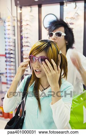 Teenage couple trying on sunglasses in shop View Large Photo Image Stock Image - Teenage couple trying on sunglasses in shop. Fotosearch