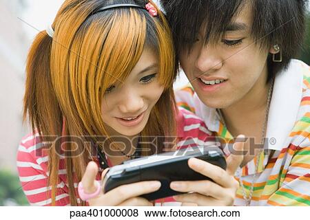 Teenage couple using portable video game View Large Photo Image Stock Photo - Teenage couple using portable video game. Fotosearch