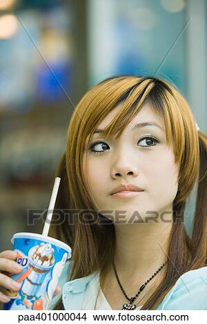 Teenage girl holding drink, looking away View Large Photo Image Picture - Teenage girl holding drink, looking away. Fotosearch