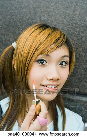 Teenage girl holding lipgloss wand View Large Photo Image Stock Photo - Teenage girl holding lipgloss wand. Fotosearch