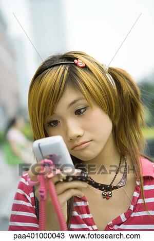 Teenage girl looking at cell phone, frowning View Large Photo Image Stock Image - Teenage girl looking at cell phone, frowning. Fotosearch