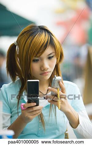 Stock Photography - Teenage girl using two cell phones. Fotosearch