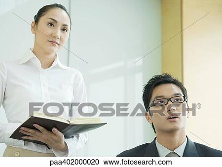 Business executive and woman holding agenda, both looking out of frame View Large Photo Image Stock Image - Business executive and woman holding agenda, both looking out of frame. Fotosearch
