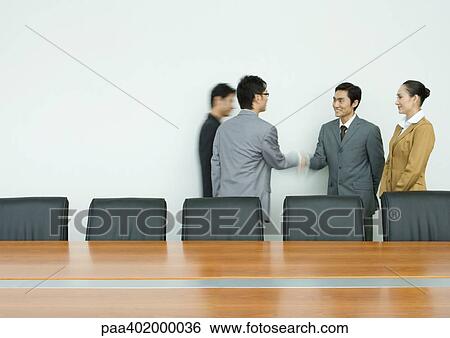 Business executives shaking hands in conference room View Large Photo Image Stock Photograph - Business executives shaking hands in conference room. Fotosearch