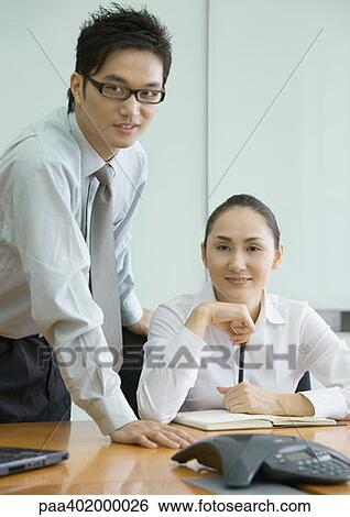 Businessman and woman in conference room, smiling at camera View Large Photo Image Stock Photograph - Businessman and woman in conference room, smiling at camera. Fotosearch