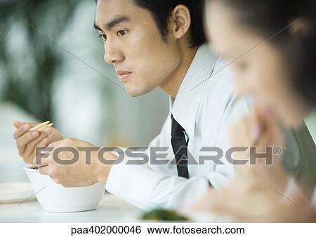 Businessman eating with chopsticks, looking away View Large Photo Image Stock Photograph - Businessman eating with chopsticks, looking away. Fotosearch