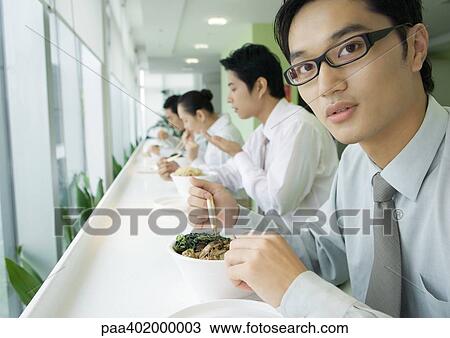 Businessman having lunch in cafeteria, looking at camera View Large Photo Image Stock Image - Businessman having lunch in cafeteria, looking at camera. Fotosearch