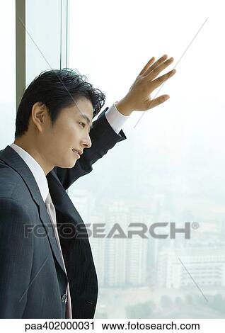 Businessman looking out of window of high rise, side view View Large Photo Image Stock Image - Businessman looking out of window of high rise, side view. Fotosearch