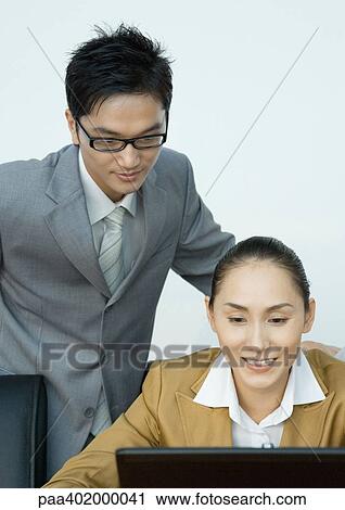 Businessman looking over female colleague's shoulder View Large Photo Image Stock Image - Businessman looking over female colleague's shoulder. Fotosearch
