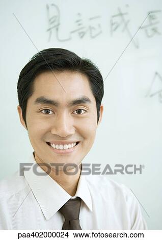 Businessman smiling, Chinese script on whiteboard in background, portrait View Large Photo Image Picture - Businessman smiling, Chinese script on whiteboard in background, portrait. Fotosearch
