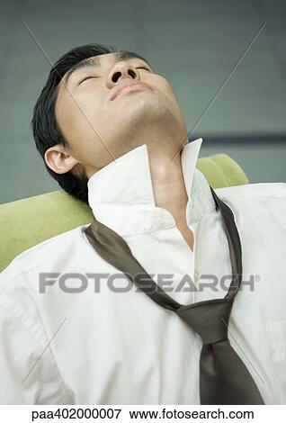 Stock Photo - Businessman wearing loosened tie, head back and eyes closed. Fotosearch