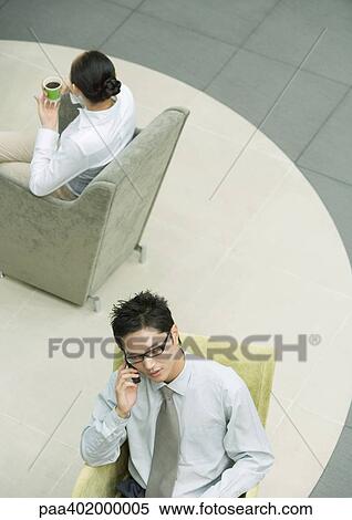 Stock Photography - Executive using cell phone in lobby. Fotosearch