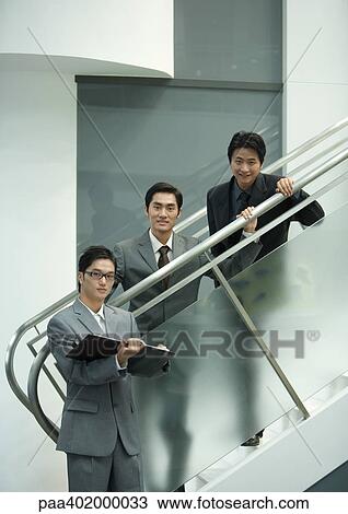 Three business executives standing along staircase, looking at camera View Large Photo Image Stock Image - Three business executives standing along staircase, looking at camera. Fotosearch