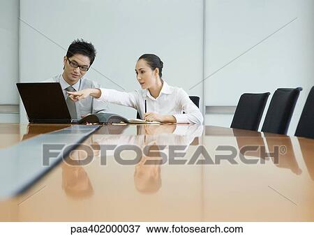 Two business executives working with laptop in conference room View Large Photo Image Stock Photo - Two business executives working with laptop in conference room. Fotosearch