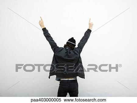 Stock Photography - Man standing with arms up, pointing with both hands, rear view. Fotosearch