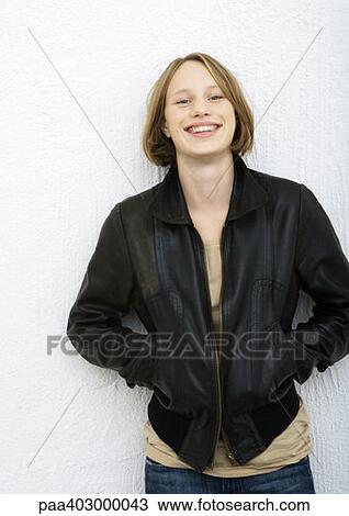 Stock Image - Teenage girl standing with hands in jacket pockets, portrait. Fotosearch