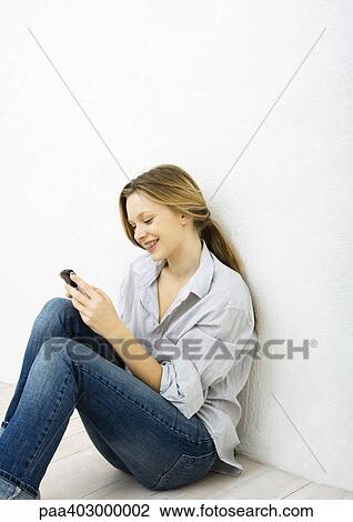 Teenage girl using cell phone, sitting on floor View Large Photo Image Stock Image - Teenage girl using cell phone, sitting on floor. Fotosearch