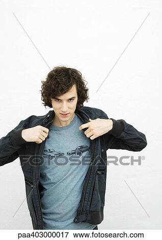 Stock Photo - Young man putting on jacket, portrait. Fotosearch
