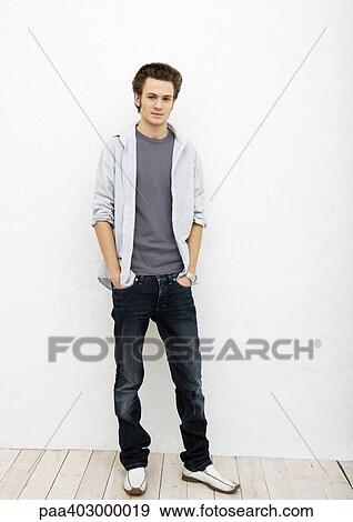 Stock Photo - Young man standing with hands in pockets, full length portrait. Fotosearch