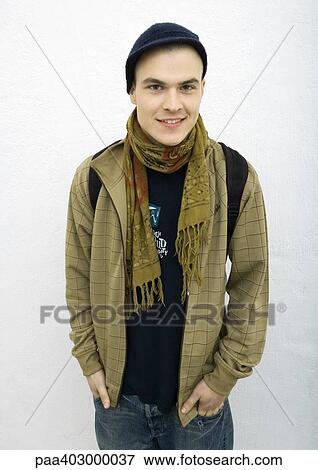 Stock Photo - Young man standing with hands in pockets, front view, portrait. Fotosearch