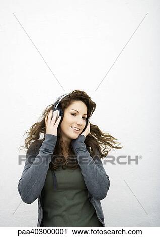 Young woman listening to headphones, white background View Large Photo Image Stock Image - Young woman listening to headphones, white background. Fotosearch