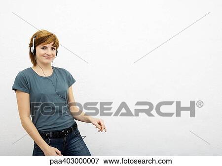 Stock Photo - Young woman listening to headphones, white background. Fotosearch