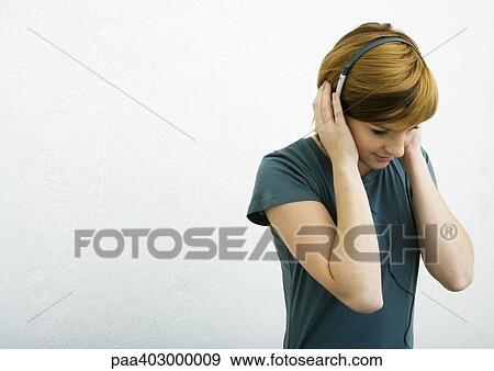 Young woman listening to headphones, white background View Large Photo Image Stock Photo - Young woman listening to headphones, white background. Fotosearch
