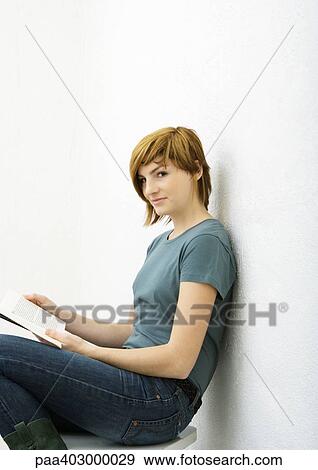 Young woman sitting with book, portrait View Large Photo Image Stock Photo - Young woman sitting with book, portrait. Fotosearch