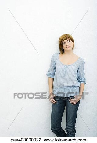 Stock Image - Young woman standing with thumbs in pockets. Fotosearch