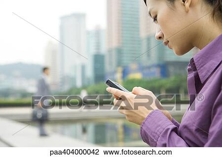 Businesswoman looking at cell phone View Large Photo Image Stock Image - Businesswoman looking at cell phone. Fotosearch