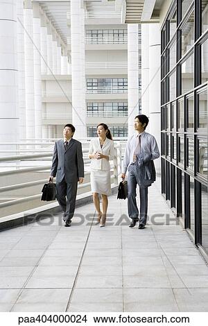 Three young executives walking side by side next to office building View Large Photo Image Picture - Three young executives walking side by side next to office building. Fotosearch