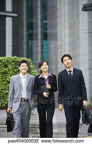 Stock Image - Three young executives walking side by side. Fotosearch