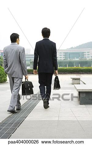 Two businessmen walking in office park, rear view View Large Photo Image Stock Photograph - Two businessmen walking in office park, rear view. Fotosearch