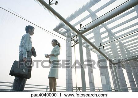 Young business executives standing under covered walkway, face to face, low angle view View Large Photo Image Stock Image - Young business executives standing under covered walkway, face to face, low angle view. Fotosearch