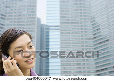 Young businesswoman using cell phone, office buildings in background View Large Photo Image Stock Photo - Young businesswoman using cell phone, office buildings in background. Fotosearch