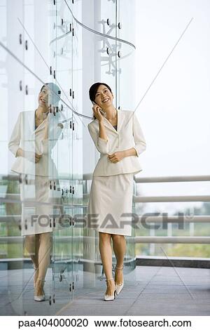 Young businesswoman walking, using cell phone and smiling, full length View Large Photo Image Stock Image - Young businesswoman walking, using cell phone and smiling, full length. Fotosearch