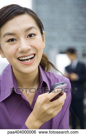 Young woman holding cell phone, laughing View Large Photo Image Stock Photograph - Young woman holding cell phone, laughing. Fotosearch