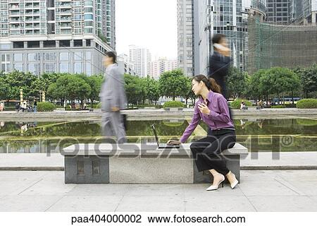 Young woman using laptop outdoors on office park bench View Large Photo Image Stock Image - Young woman using laptop outdoors on office park bench. Fotosearch