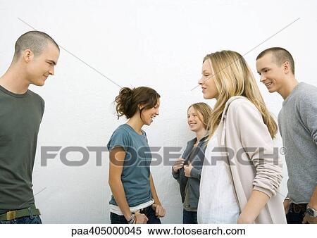 Stock Photography - Group of casually dressed young adults, moving toward each other, side view, white background. Fotosearch