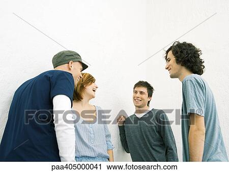 Stock Image - Group of young adult friends standing in group, laughing. Fotosearch
