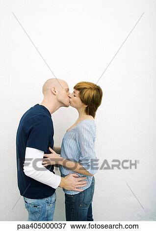 Stock Photo - Young couple kissing, hands on each other's waists. Fotosearch