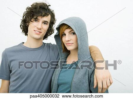 Stock Image - Young couple, man with arm around woman's shoulders, portrait. Fotosearch