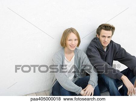 Young man and woman sitting on ground, leaning against wall View Large Photo Image Stock Photo - Young man and woman sitting on ground, leaning against wall. Fotosearch