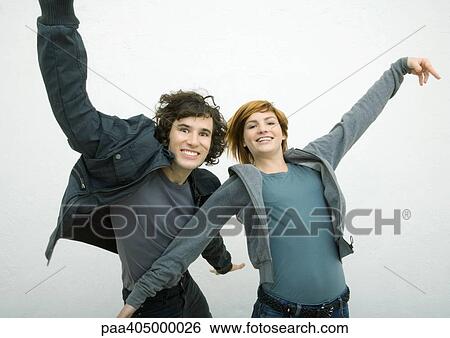 Stock Photograph - Young man and young woman dancing with arms out, smiling at camera. Fotosearch