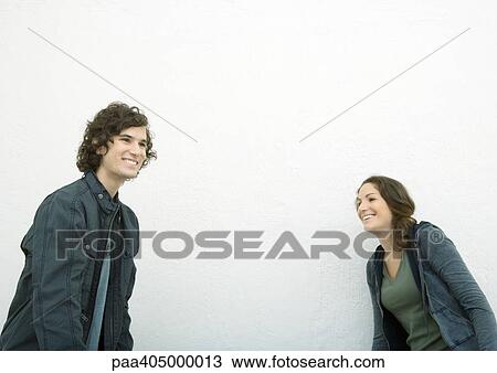 Young man and young woman, standing apart, laughing and looking away View Large Photo Image Stock Image - Young man and young woman, standing apart, laughing and looking away. Fotosearch