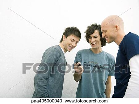 Stock Image - Young man showing two male friends cell phone. Fotosearch