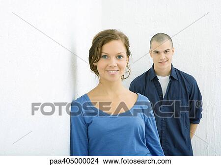 Picture - Young woman smiling at camera, young man behind her smirking. Fotosearch