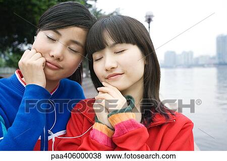 Two friends sharing earphones, eyes closed View Large Photo Image Stock Photo - Two friends sharing earphones, eyes closed. Fotosearch