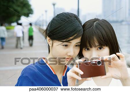 Stock Photo - Two young friends taking photo with digital camera. Fotosearch
